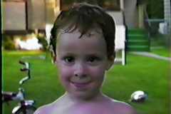 Dave Arnold playing with the sprinkler in back yard at Fourth Street home, July 1986.